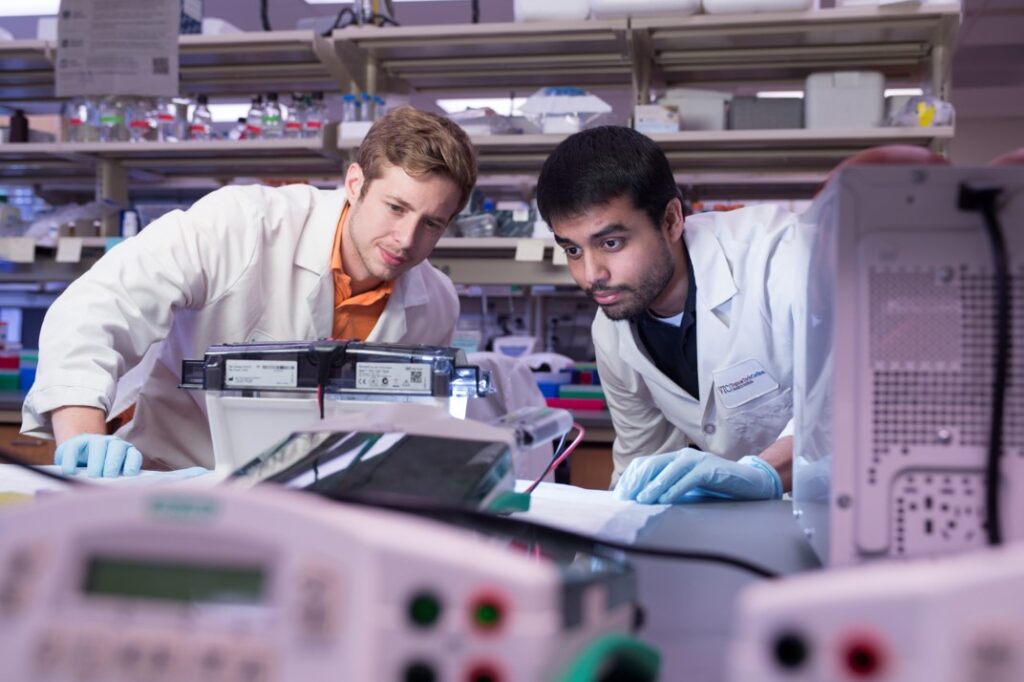 Two men in lab coats examining their work