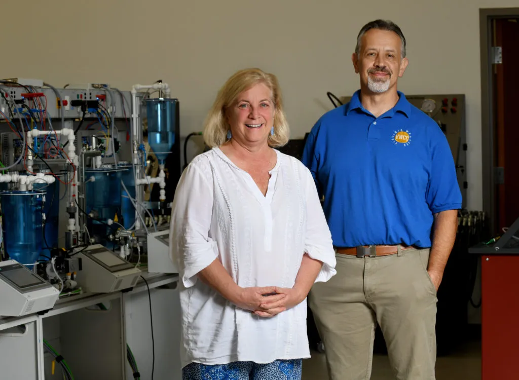 Photo of man and woman in front of lab equipment